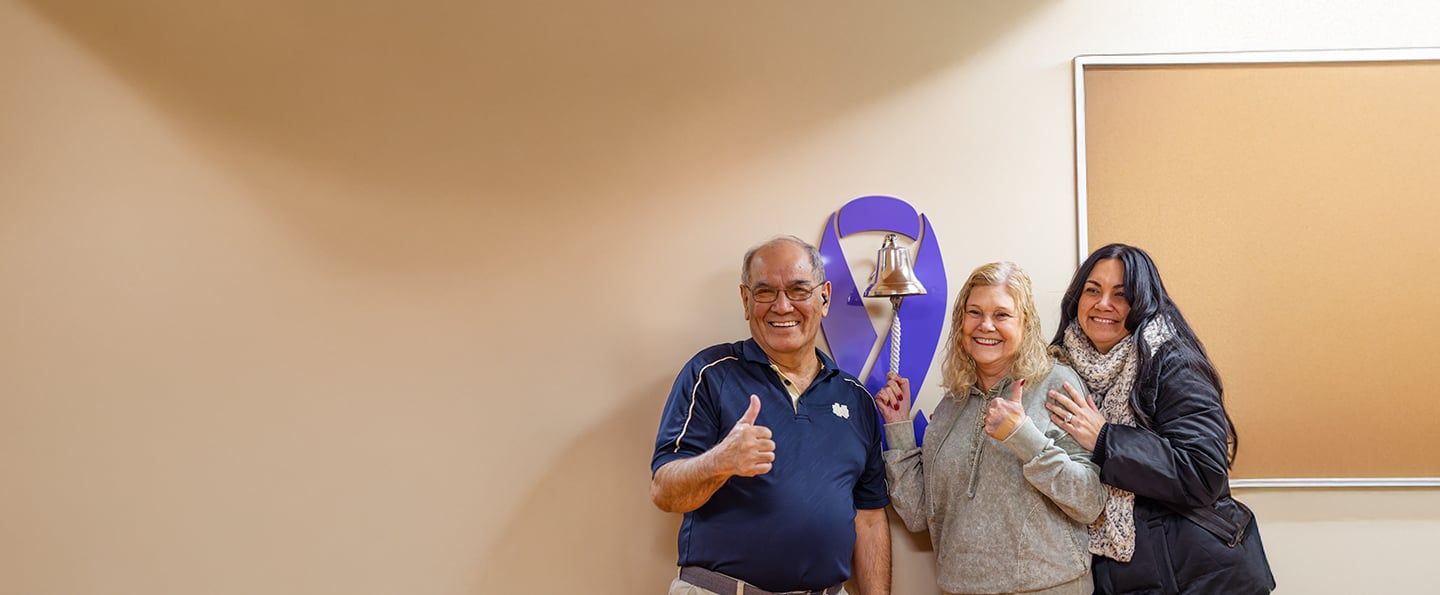 A cancer patient ringing the bell after her last treatment with her family surrounding her