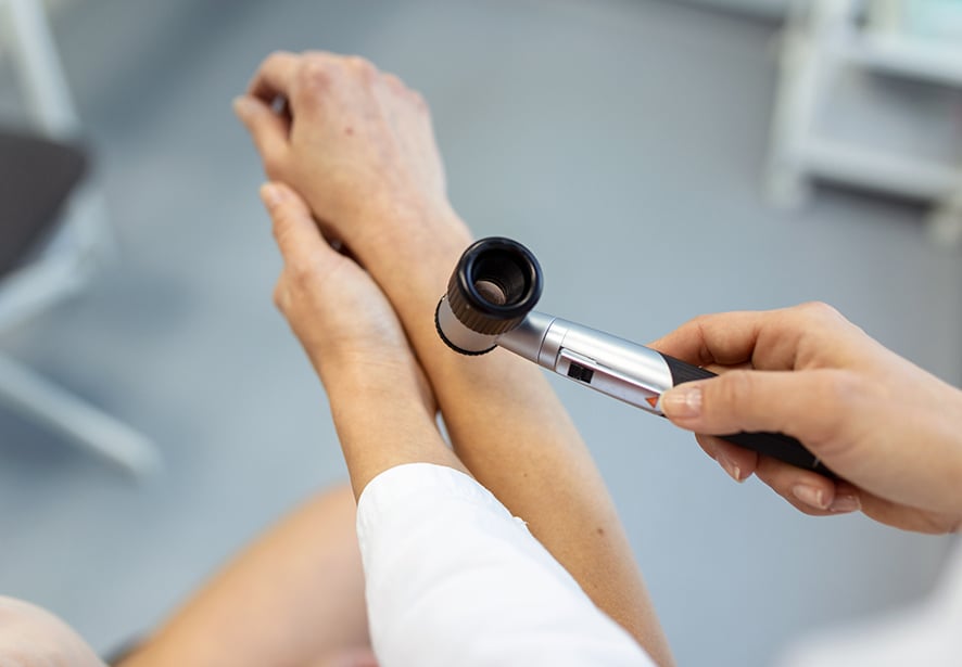 A doctor using a dermatoscope while doing the skin examination