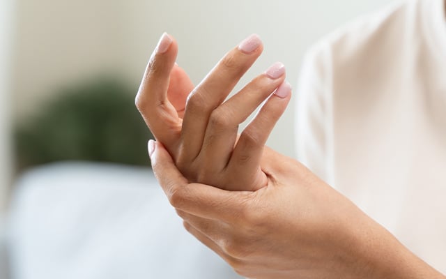 A close-up image of a woman handing her hand rubbing it.