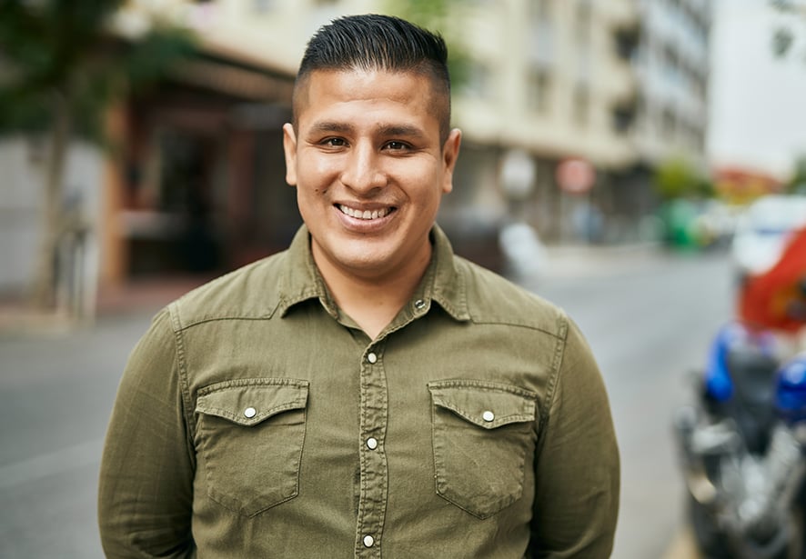 A Hispanic man smiling in a downtown setting