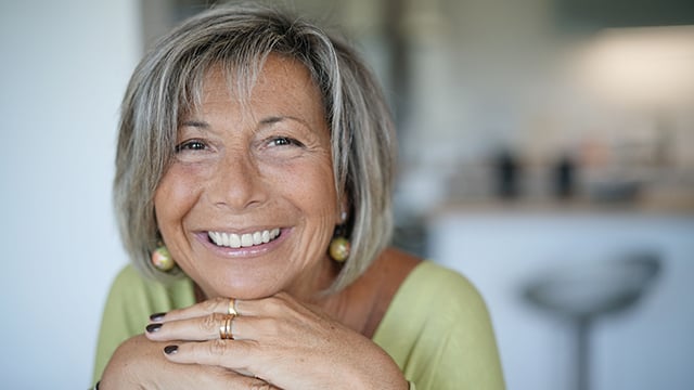 A woman resting her chin on her hands smiling