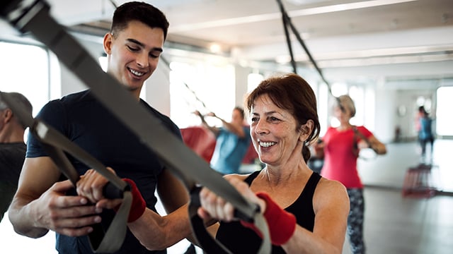 A woman working out in a gym setting with a young male trainer 