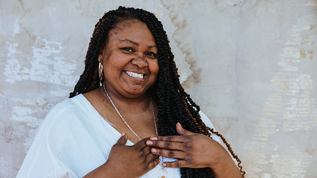 A woman smiling with her hands near her heart