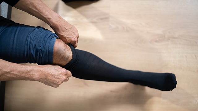 Up close image of a man putting on medical compression socks
