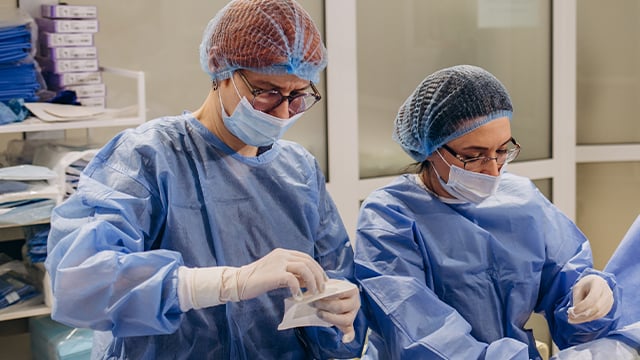 Two medical professions working in the operating room together.