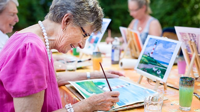 An older woman painting with other women
