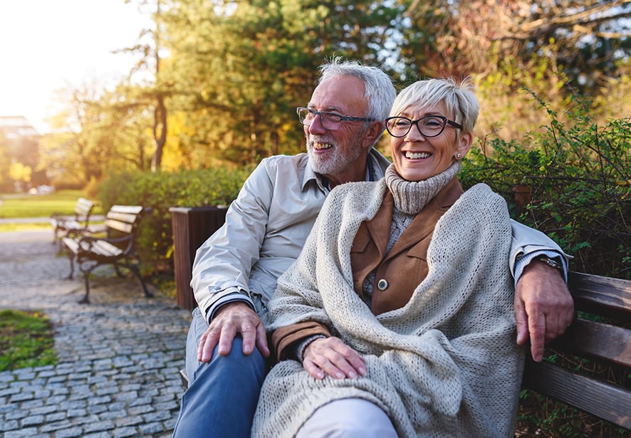 A man and women sitting on a bench in a park