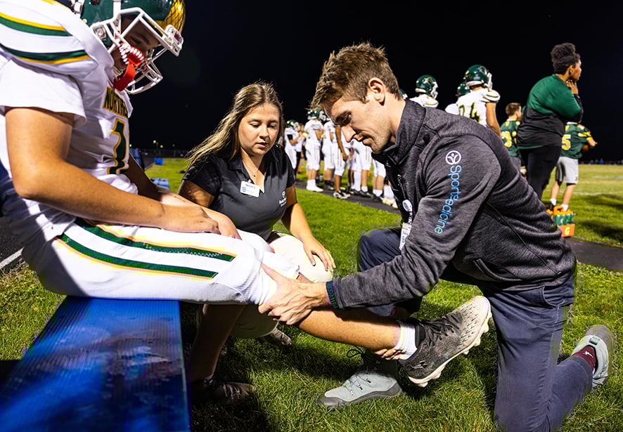 Reid Health Sport Medicine Sport Surgeon Dr. Connor Hoban and AT-C Hannah Cupp working on a student athlete