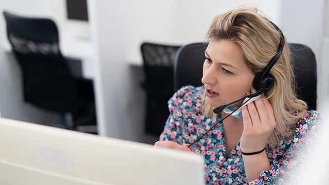 A lady customer service worker talking on a headset 