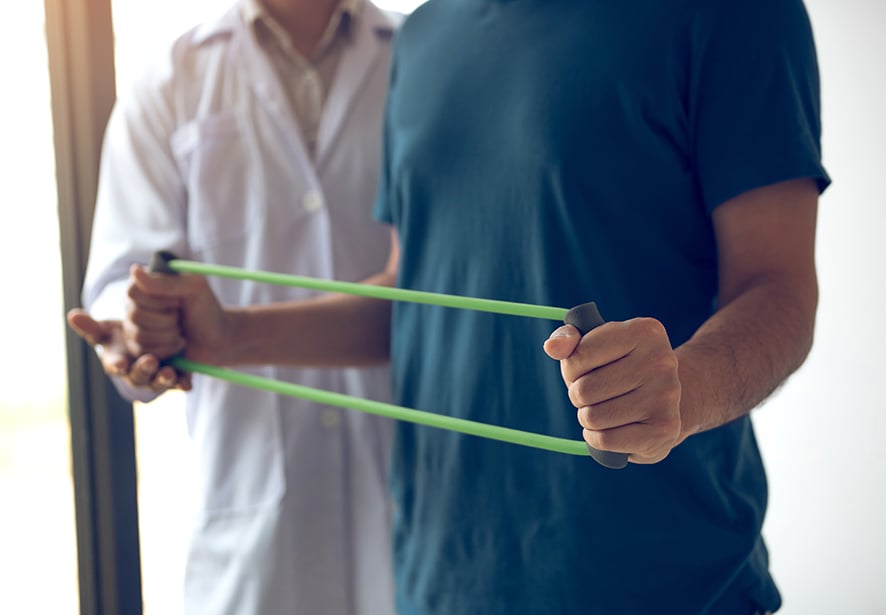 A close up image of a man using an exercise rubber band 