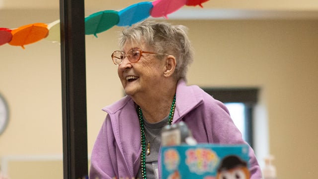 A close up view of a PACE participant smiling at her care team