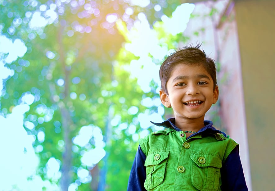 A young Hispanic boy standing outside smiling
