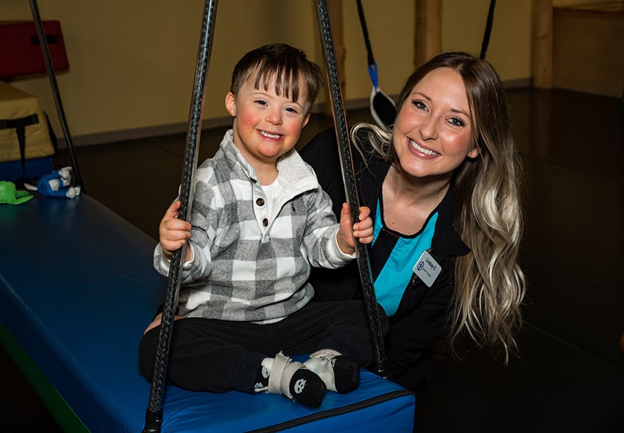 A young boy smiling will sitting on a swing