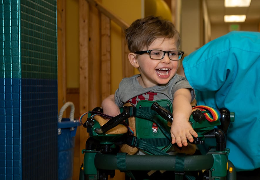A young boy smiling while doing gait therapy 