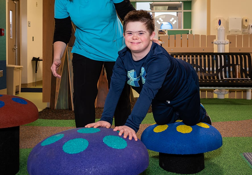 A young boy crawling across therapy equipment 