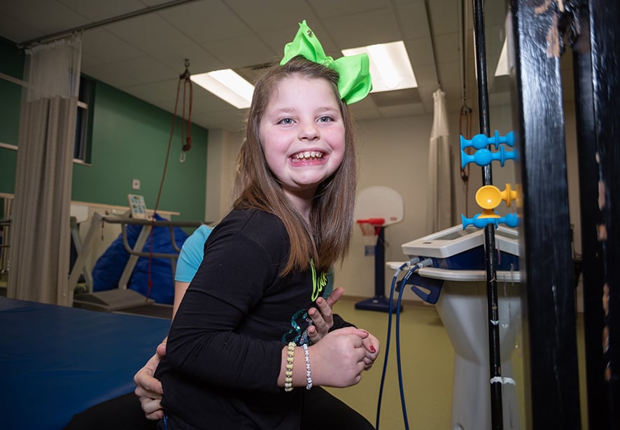 A young girl smiling while doing pediatric therapy