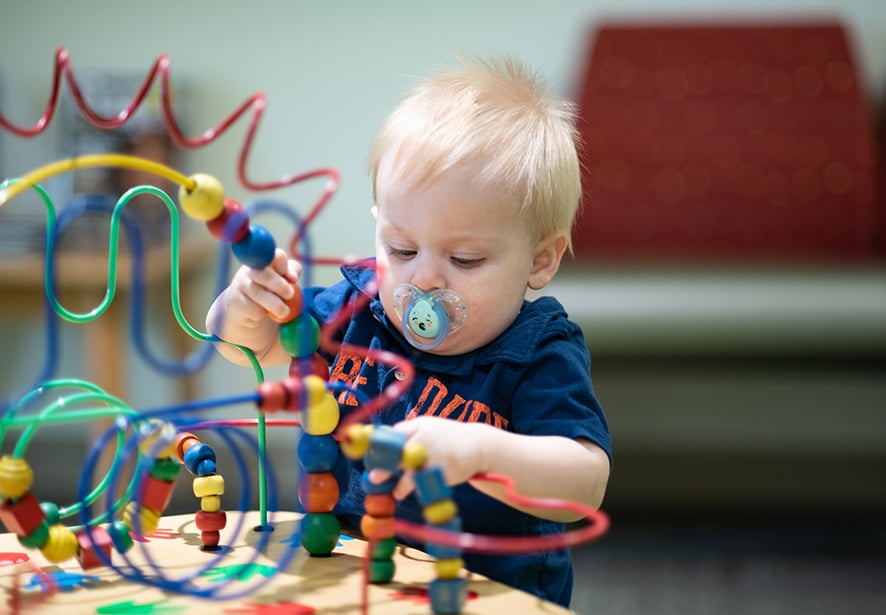 A toddler boy playing in the waiting room with toys