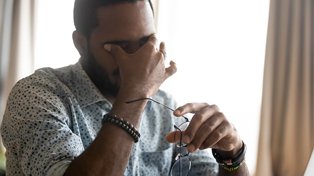 A man rubbing head and eyes because of a migraine 