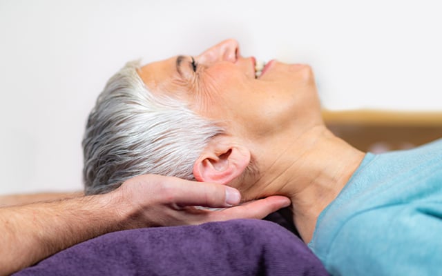 A close-up view of a woman laying on her back with a provider hands under her head