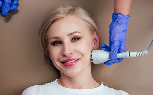 A woman smiling while receiving a Legend Pro treatment