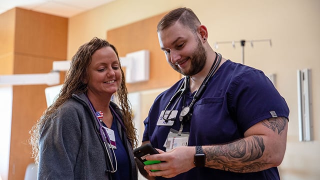 A male nurse showing a female nurse how to use the volt technology 