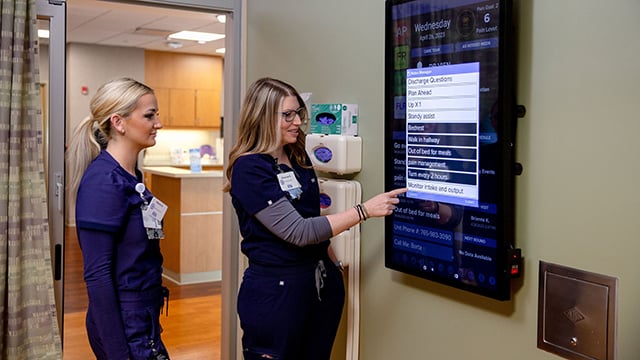 Two Reid Health nurses using the smart board technology in a patient room