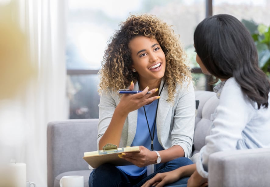 A woman with a clip board talking with another woman