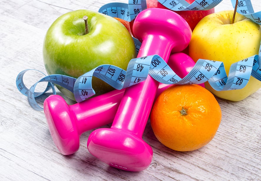 An image showing free weights, fruits, and a tape measure to prompt a healthy lifeststyle