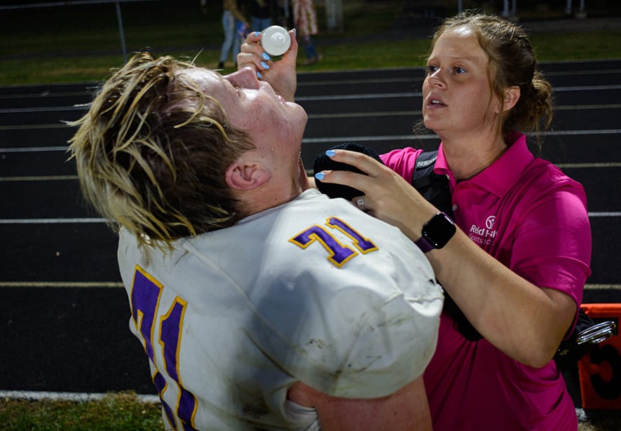 Reid Health's Athletic Trainer, Maria Duckworth providing aid to a Hagerstown football player