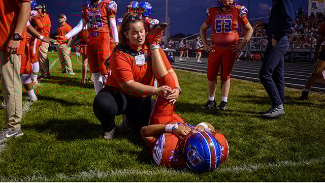 Dorothy Tyo, Reid Health Athletic Trainer, stretching a Union City High School football player 