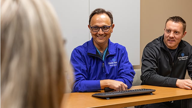 Dr. Aaron Johnson smiling at his team with Tyler Thompson, NP sitting beside him