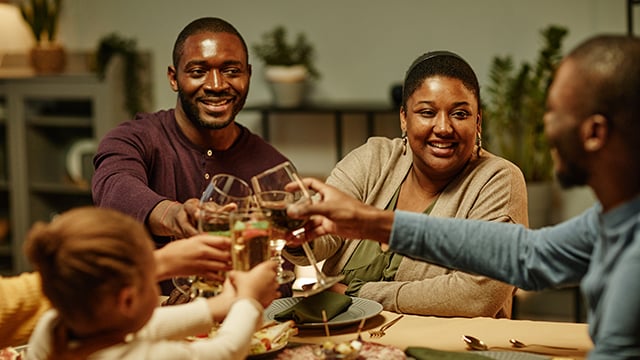 A African American man sitting at the dinner table with family and friends smiling