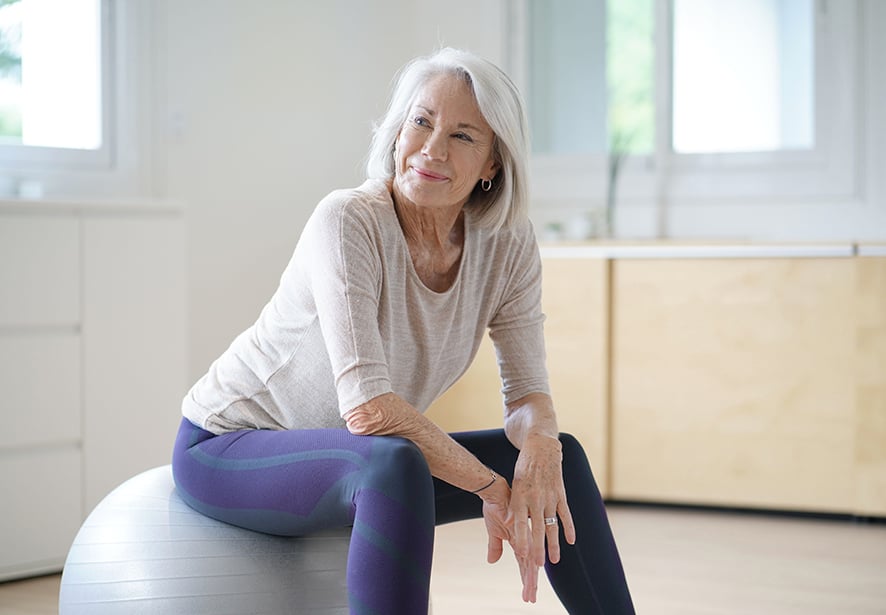 An older woman sitting on an exercise ball