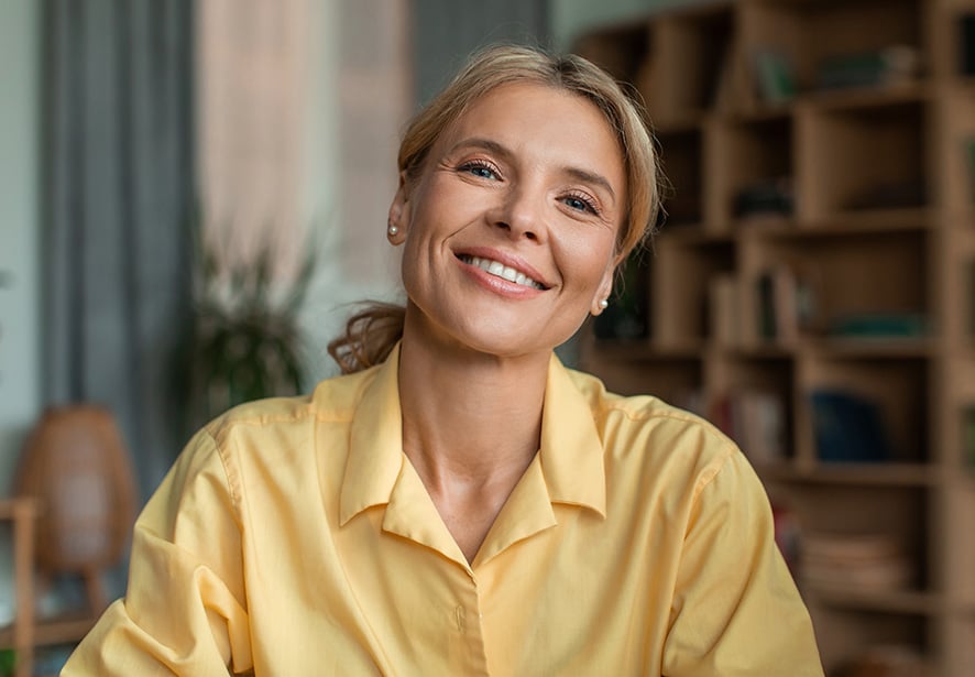 A women wearing a yellow shirt smiling for the camera