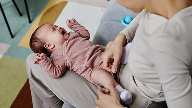 A baby laying her caregivers lap crying