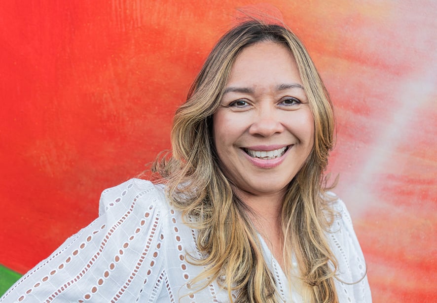 Smiling Hispanic woman with blond hair against colorful wall