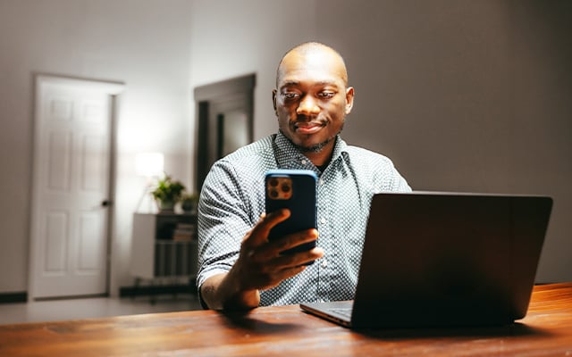 A adult male looking at his phone in a home/work environment 