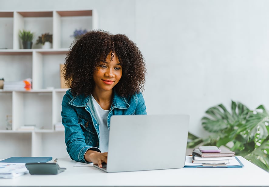Close up portrait of a woman smiling and using laptop computer.