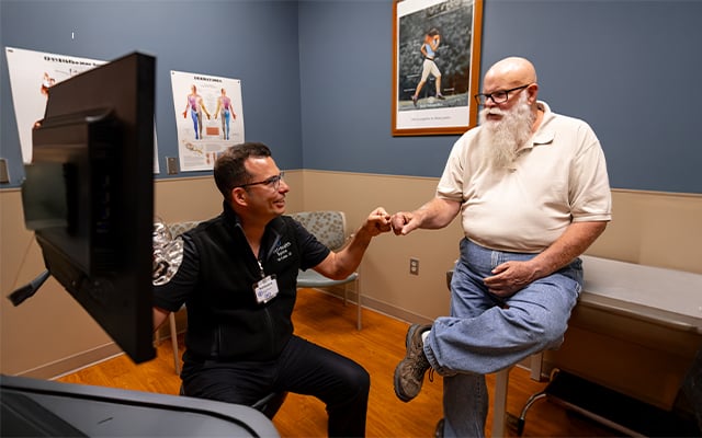 Reid Health Spine Surgeon, Ted Kostiuk, DO fist bumping a patient after a successful surgery. 