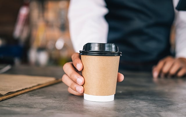 A barista placing a coffee on a counter 
