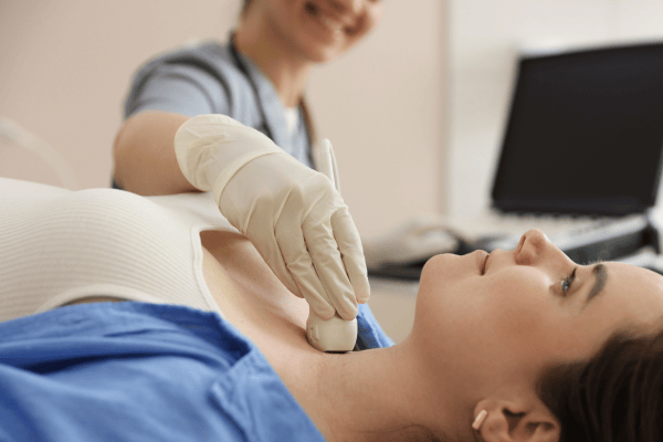 Image is of a care provider that is administering a vascular scan with an ultrasound probe on the patients neck. The patient is relaxed and comfortable. 