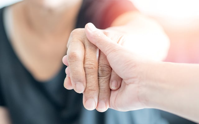An up-close image of person holding another person hand.