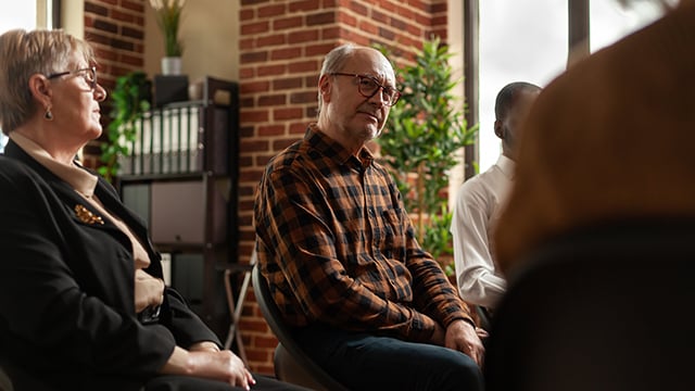 A group of people sitting in a group session listening to a speaker