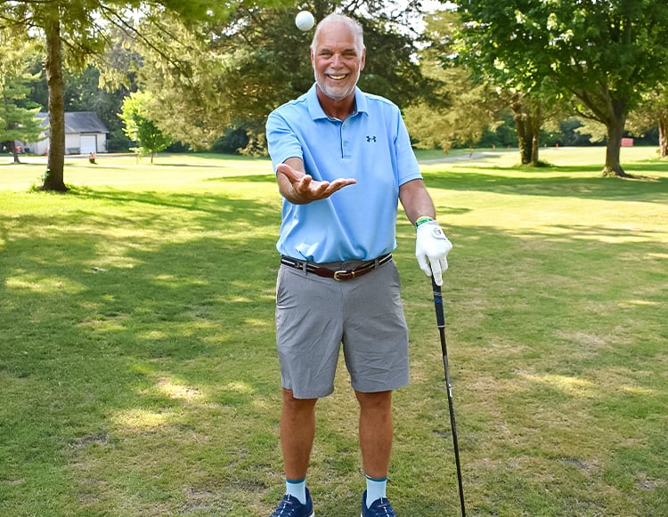  Scott Blazak’s, an Inspire patient smiling at the gold course while tossing a ball up in the air