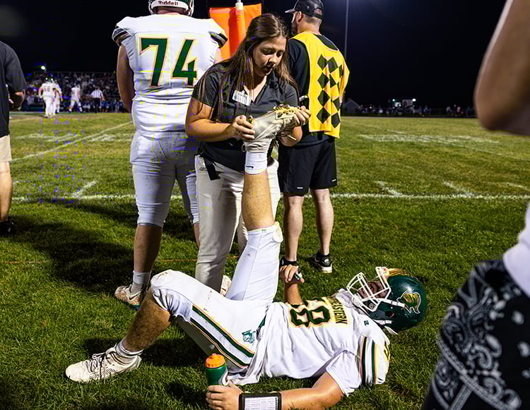 Reid Health Athletic Trainer, Hannah Cupp stretching a Northeastern football player 
