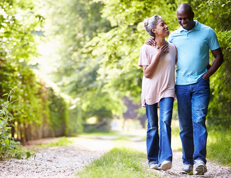A man and woman walking together on a trail with the man arm behind the woman's back