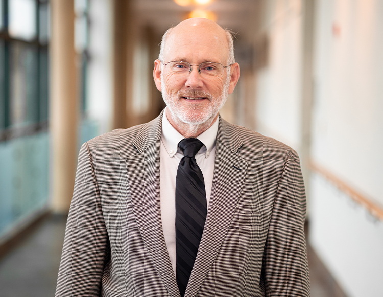 Donald Smith, MD, recipient of the 2026 Rhoads Humanity in Medicine Award, smiles for a professional portrait wearing glasses, a gray suit jacket, and a black tie.