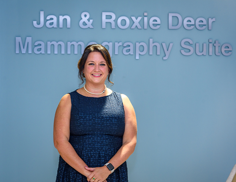 Roxie Deer smiling and standing in front of the Jan & Roxie Deer Mammography Suite during the dedication ceremony at Reid Health Connersville.