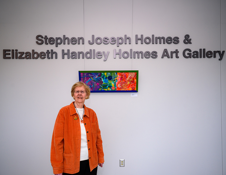 Elizabeth Holmes smiling and standing in front of the Stephen Joseph Holmes & Elizabeth Handley Holmes Art Gallery during the dedication ceremony at Reid Health Connersville.