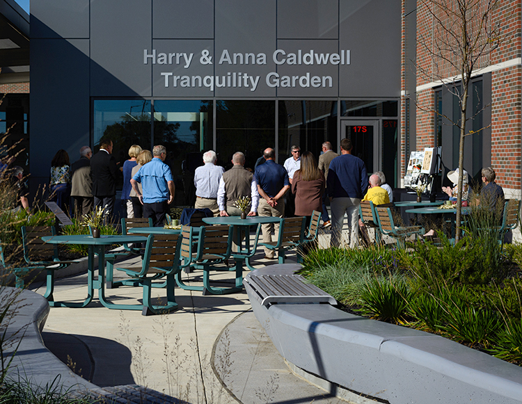 An outside view of the Harry and Anna Caldwell Tranquility Garden with a crowd gathering at the dedication ceremony on September 29, 2026 at Reid Health Connersville.